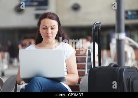 Femme avec un ordinateur portable dans l'aéroport, à l'aide d'une connexion internet, traveler vérification du courrier électronique Banque D'Images