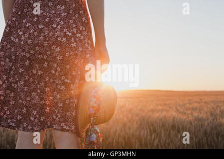 Concept d'attente ou d'adieu, le coucher du soleil, d'été femme hand holding hat Banque D'Images