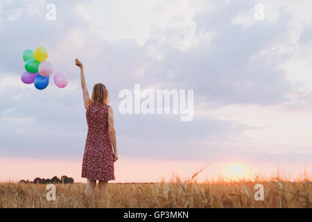 Concept d'espoir, d'émotions et sentiments, femme avec des ballons colorés dans le domaine, l'arrière-plan Banque D'Images