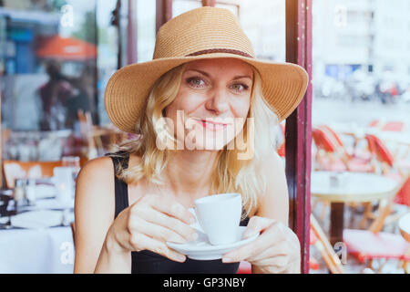 Portrait of fashion belle femme d'âge moyen en café avec tasse de café, heureux, souriant et regardant la caméra Banque D'Images