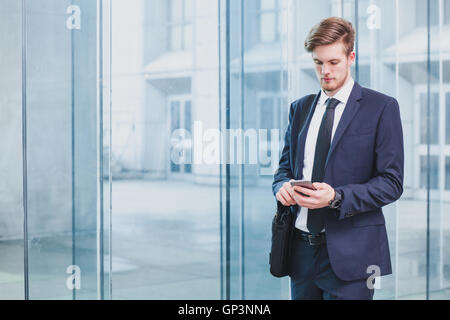 Businessman using smartphone près de l'immeuble de bureaux Banque D'Images
