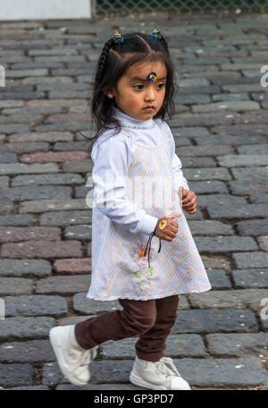 Une mignonne petite fille courir sur le pavé en pierre Plaza de San Francisco dans le quartier historique de la vieille ville de Quito, en Équateur. Banque D'Images