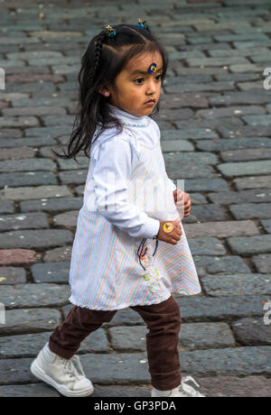 Une mignonne petite fille courir sur le pavé en pierre Plaza de San Francisco dans le quartier historique de la vieille ville de Quito, en Équateur. Banque D'Images
