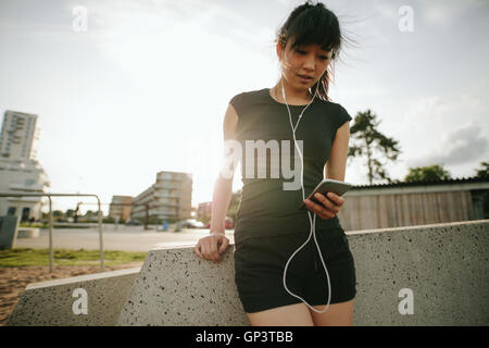 Portrait d'une belle jeune femme sportive et l'écoute de musique ayant une pause après l'exécution de l'extérieur. Banque D'Images