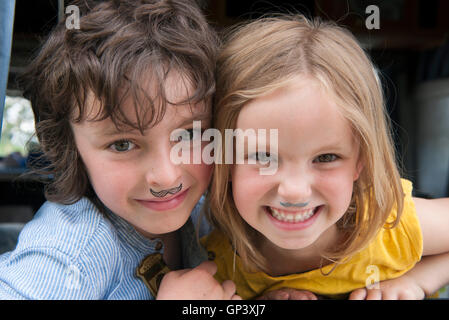 Les jeunes frères et sœurs portant de fausses moustaches, portrait Banque D'Images