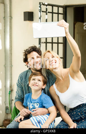 Famille avec un enfant posant pour prises selfies with digital tablet Banque D'Images