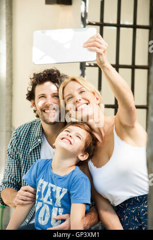Famille avec un enfant posant pour prises selfies with digital tablet Banque D'Images
