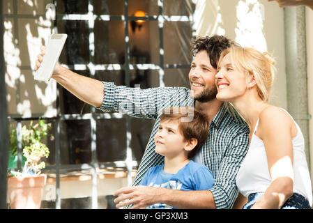 Famille avec un enfant posant pour prises selfies with digital tablet Banque D'Images