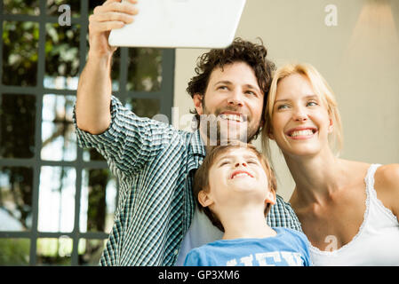 Famille avec un enfant posant pour prises selfies with digital tablet Banque D'Images