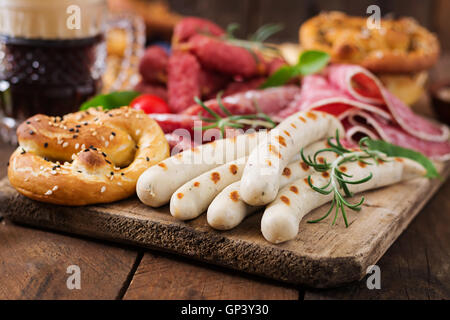 Verre de bière, les bretzels et diverses saucisses sur fond de bois. L'Oktoberfest. Banque D'Images