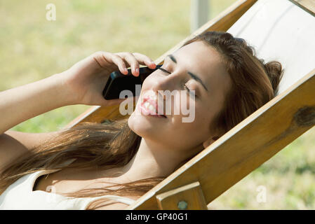 Woman talking on cell phone while sunbathing Banque D'Images