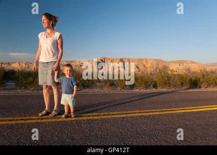 La mère et le petit garçon marcher ensemble sur la route pavée à travers désert Banque D'Images