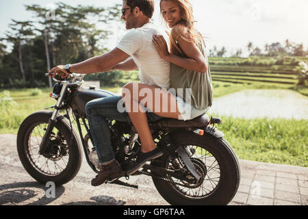 Tourné en plein air de happy young couple moto ride on country road. Femme assise à l'arrière et l'homme moto thr Banque D'Images