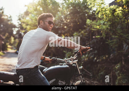 Portrait de beau jeune homme sur la moto. Heureux homme de race blanche en moto à la recherche de là et souriant. Banque D'Images