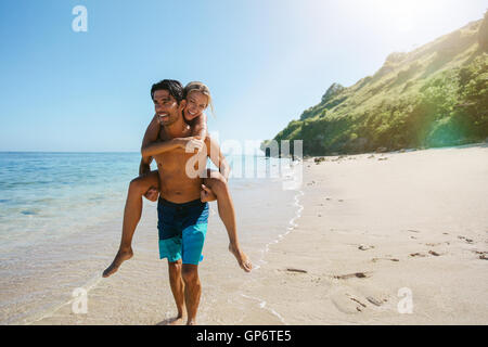 Couple heureux en amour plage vacances d'été. Femme joyeuse greffant sur l'ami, le jeu et le plaisir sur le voyage vacatio Banque D'Images