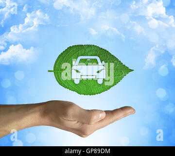 Ouvert main tenant une feuille verte avec une icône de voiture à l'intérieur sur un fond de ciel bleu. Concept de voiture écologique Banque D'Images