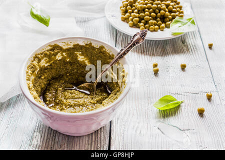 Sauce au pesto fait maison en blanc vintage bol, feuilles de basilic frais et de haricots verts sur fond de bois Banque D'Images
