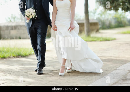 Mariée et le marié à marcher ensemble dans un parc à jour de mariage Banque D'Images