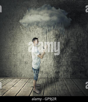 Garçon se tenir dans une chambre, la tenue d'un nuage orageux et pluvieux comme parapluie. Le pessimisme des entreprises concept Banque D'Images