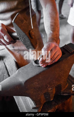 Le forgeron forge fer rougeoyant avec marteau sur l'enclume de forgeron Banque D'Images