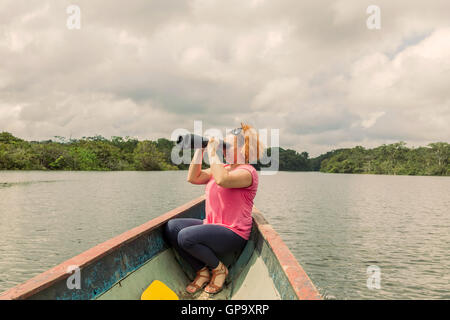 Happy Blonde Femme avec des jumelles de haute puissance dans la jungle amazonienne, Parc National Cuyabeno, Amérique du Sud Banque D'Images