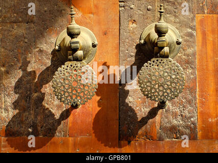 Poignées de porte en bronze d'ornement décoré les portes de palais marocain au soleil du soir Banque D'Images