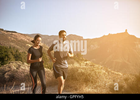 Jeune couple en marche dans les montagnes en fin d'après-midi soleil tout en portant des vêtements décontractés Banque D'Images