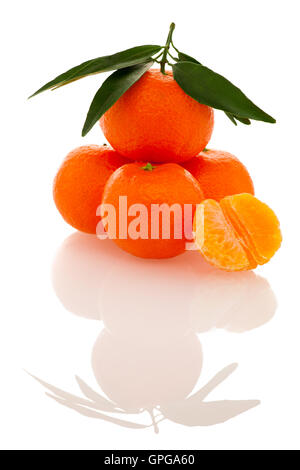 Agrumes mandarin orange fraîches non pelées avec feuilles vertes et la moitié des tranches de fruits pelés isolated over white background. Tasty swe Banque D'Images