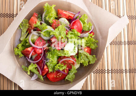 Vue de dessus sur une assiette avec salade de légumes crus sur le fond de papier d'emballage et bambou. Banque D'Images