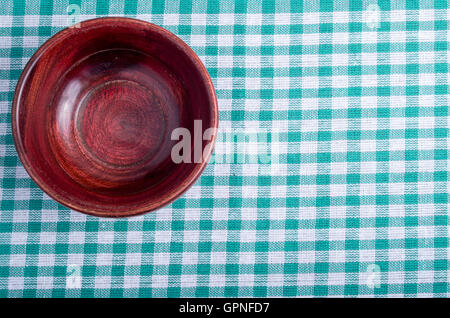 Vue de dessus de la surface de la table avec nappe à carreaux, sur lequel se dresse un petit bol en bois vide Banque D'Images