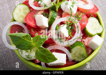 Voir Gros plan sur un bol vert avec une salade de morceaux de légumes crus hachés Banque D'Images