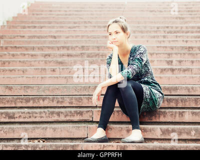 Sad girl sitting on steps Banque D'Images