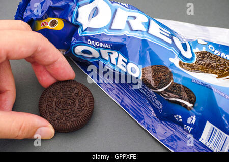 Tambov, Fédération de Russie - le 12 août 2016 Femme hand taking dernière biscuit Oreo et froissées emballage vide. Studio shot. Banque D'Images