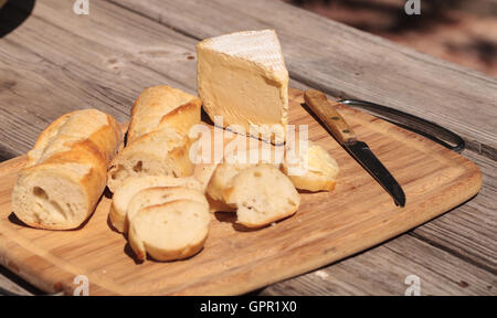 Pain français et fromage brie triple crème sur une planche à découper avec un couteau. Banque D'Images