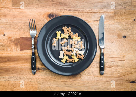 La nourriture pour chien en forme d'os dans une assiette et couverts. Vue d'en haut. Banque D'Images