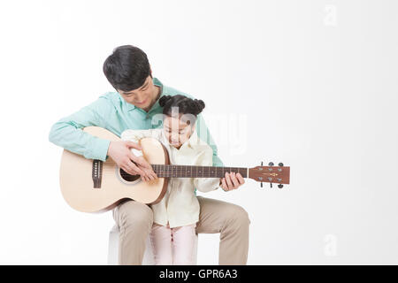 Le père aimant et sa fille jouant de la guitare Banque D'Images