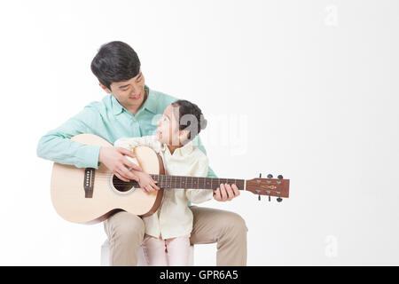 Le père aimant et sa fille jouant de la guitare Banque D'Images