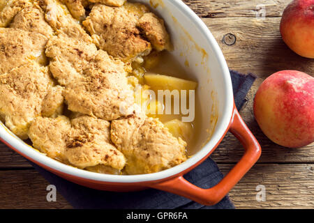 Des peach cobbler (s'effriter) dans le plat de cuisson sur fond de bois rustique Banque D'Images