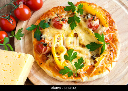 Pizza aux légumes et ingrédients sur conseil cuting en bois Banque D'Images