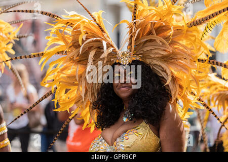 Beau noir West Indies femme portant un costume jaune très colorées et de plumes dans la coiffure de Notting Hill Carnival Banque D'Images