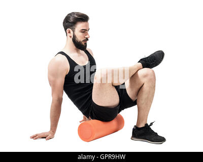 Les muscles fessiers massage sportif avec rouleau en mousse. La pleine longueur du corps portrait isolé sur fond blanc studio Banque D'Images