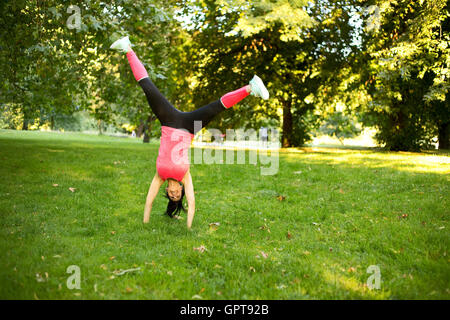 Girl effectuant une roue dans le parc Banque D'Images