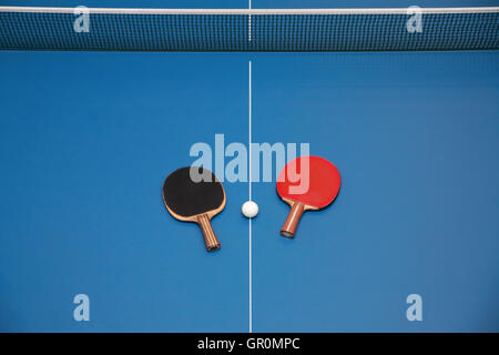 Pour raquettes de tennis de table de couleur rouge et noir et d'une balle sur une table de ping-pong, vue de dessus Banque D'Images