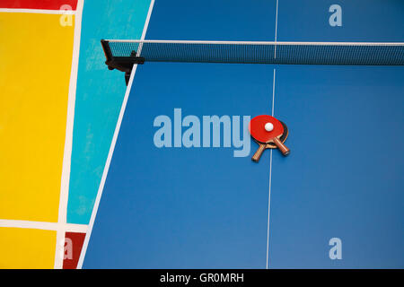 Pour raquettes de tennis de table bleu de couleur rouge et noir et d'une balle sur une table de ping-pong, vue de dessus Banque D'Images