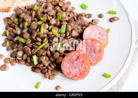 Lentilles vertes avec saucisse de porc (cotechino) on white plate Banque D'Images