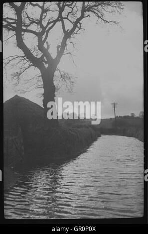 1938, historique, petite livraison de van fait son chemin à travers l'eau sur un chemin de campagne inondée près de Chagford, Devon, Angleterre, sur le bord de la Parc National de Dartmoor et à proximité de la rivière Teign. Banque D'Images