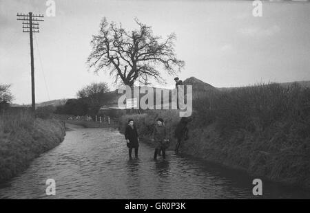 1938, historiques, les villageois patauger dans l'eau sur un chemin de campagne inondée près de Chagford, Devon, Angleterre, sur le bord de la Parc National de Dartmoor et à proximité de la rivière Teign. Banque D'Images