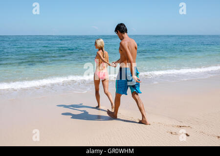 Pleine de longueur pour aller nager dans la mer. Femme tenant la main de son petit ami en marchant sur le bord de la mer. Coup Banque D'Images