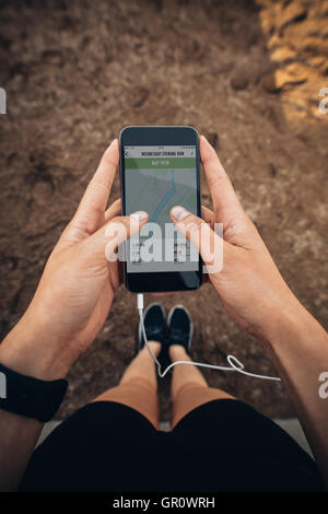 POV shot of female runner fitness à l'aide d'une application sur son téléphone mobile. Contrôle de la femme résumé de son exécution sur smartphone. Banque D'Images