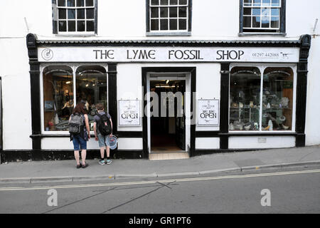 Les personnes à la recherche dans la fenêtre de la boutique fossile Lyme à Lyme Regis, dans le Dorset England UK KATHY DEWITT Banque D'Images